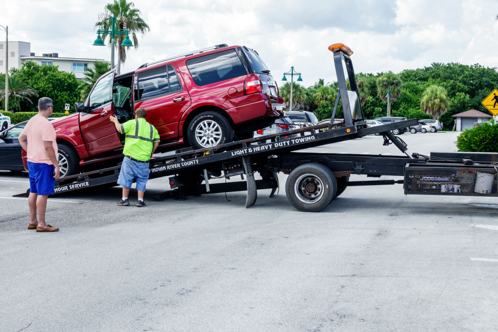 A red SUV being loaded onto the back of a flatbed tow truck