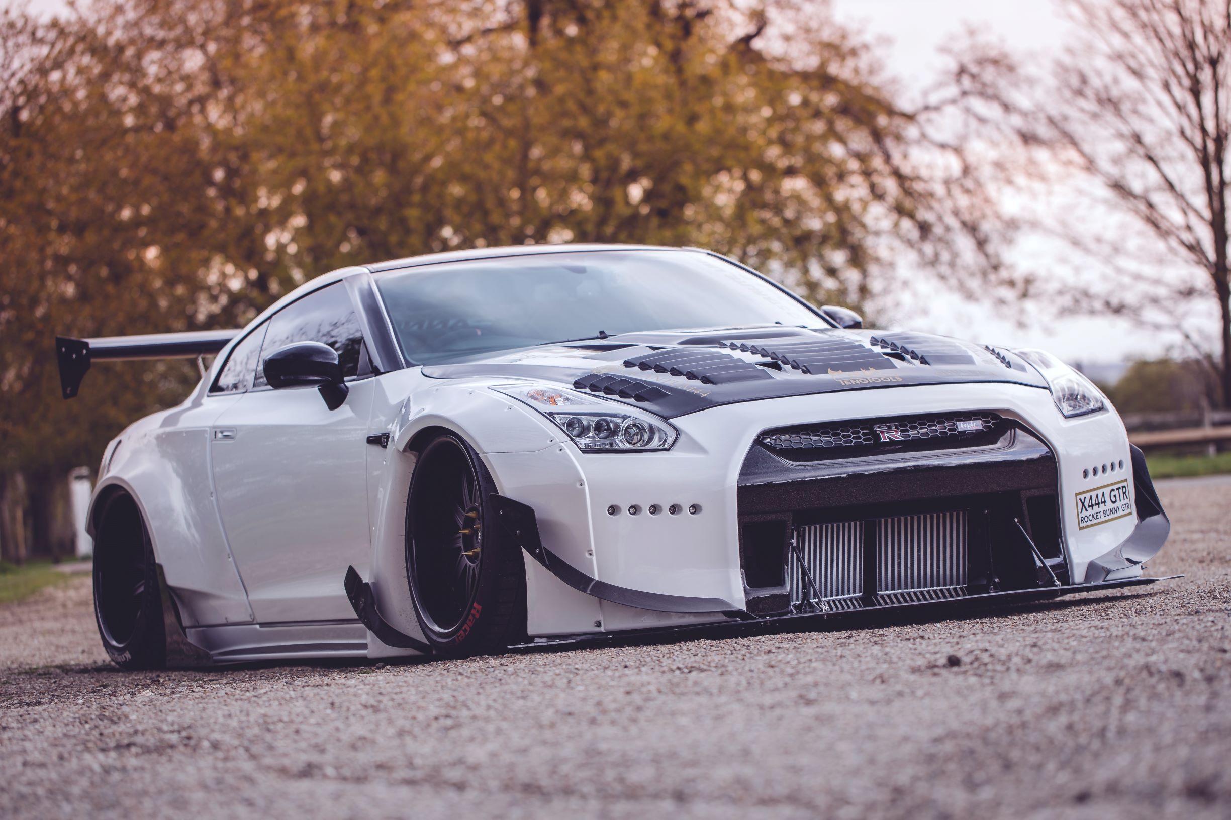 Starlite Limos' black-and-white R35 Nissan GT-R with a Rocket Bunny body kit parked in an English countryside manor garden