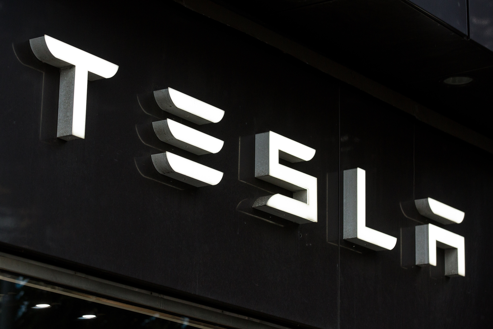 A white Tesla logo on a black wall