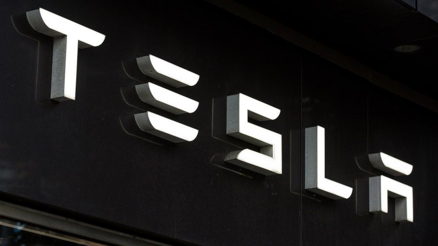 A white Tesla logo on a black wall