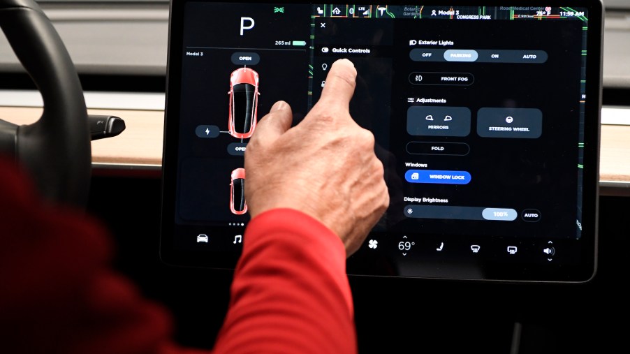 A man's finger touches a Tesla Model 3's 15-inch control touchscreen in May 2018