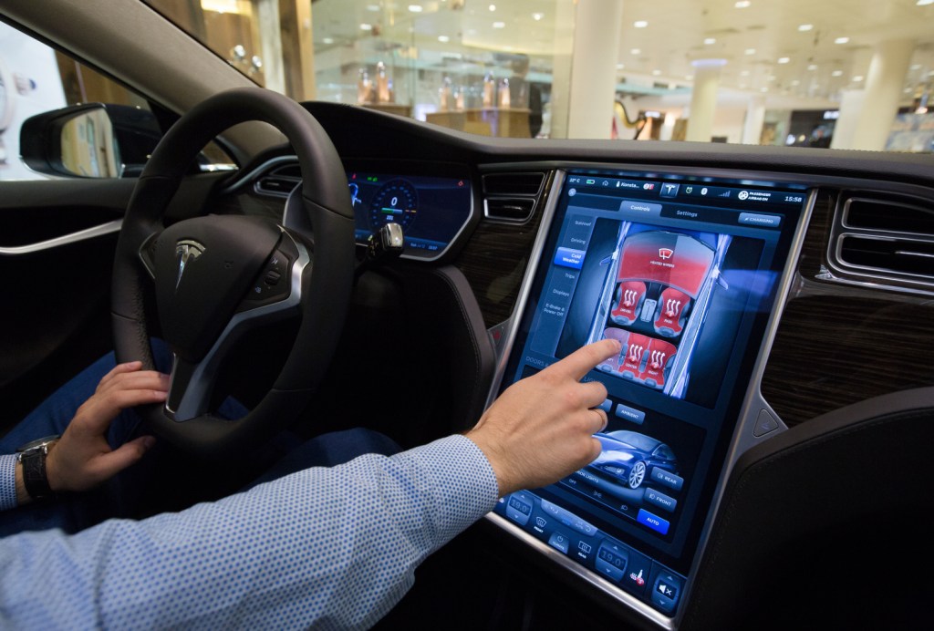A Tesla electric vehicle driver using the touch screen on a Model S