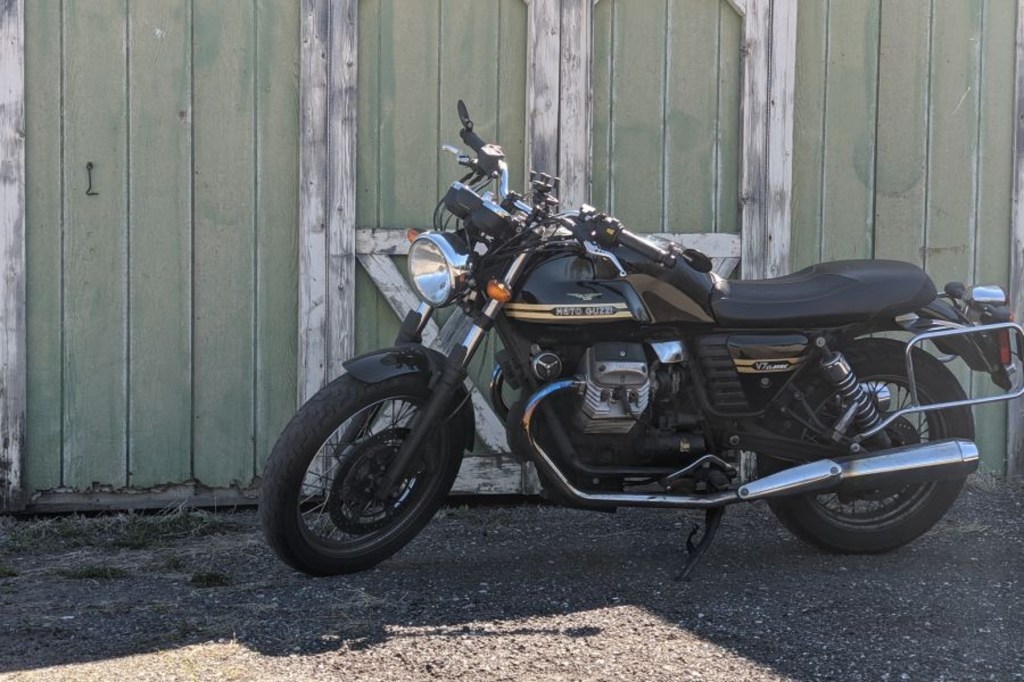 Twisted Road founder Austin Rothbard's black-and-gold 2010 Moto Guzzi V7 Classic next to a green warehouse
