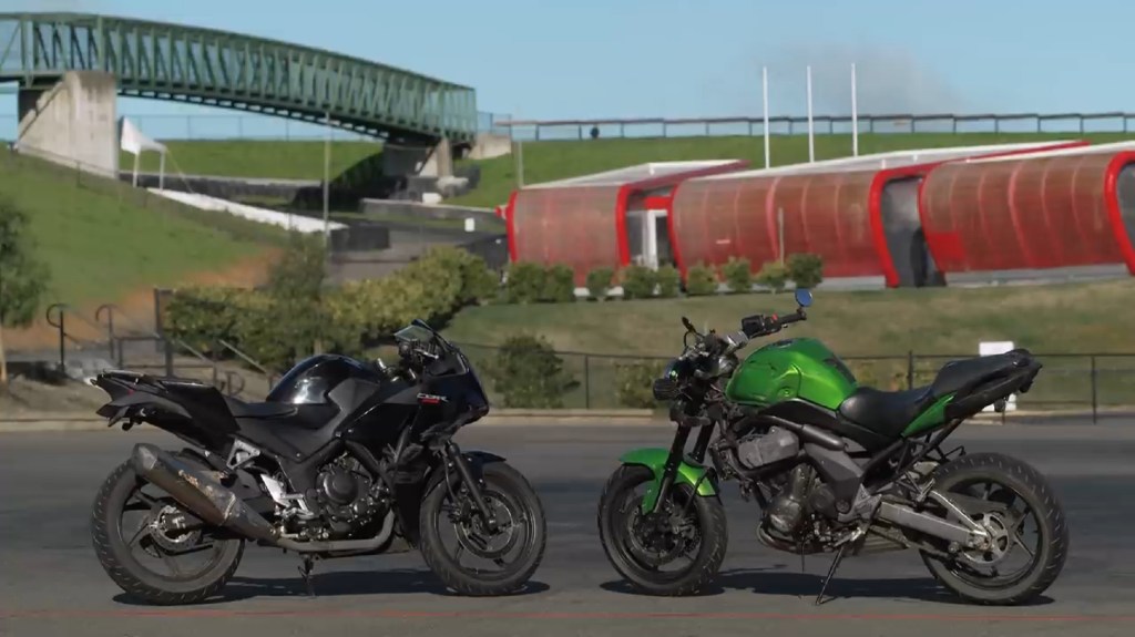 Side 3/4 views of a used black 2015 Honda CBR300R next to a used green 2009 Kawasaki Versys 650 next to a racetrack
