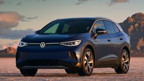 A blue 2021 Volkswagen ID.4 on a dusty lakebed by some desert mountains