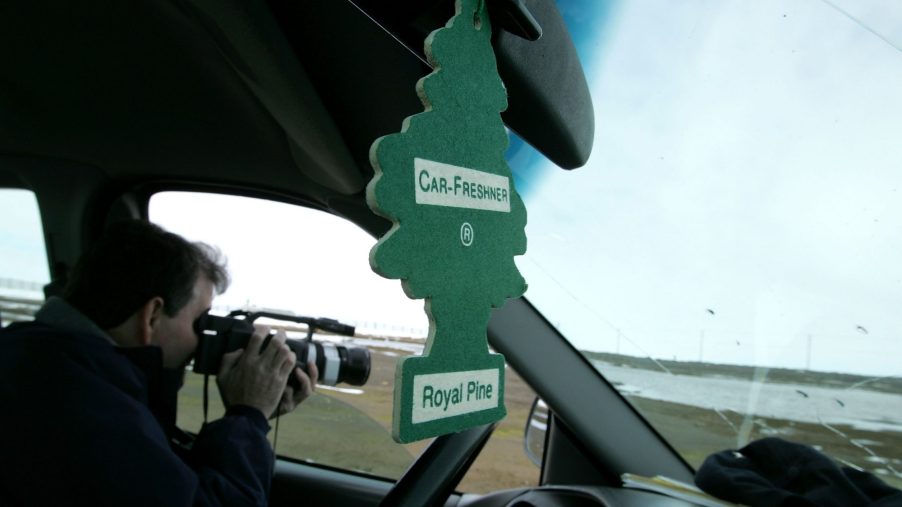 A car air freshener hangs from a car's rearview mirror