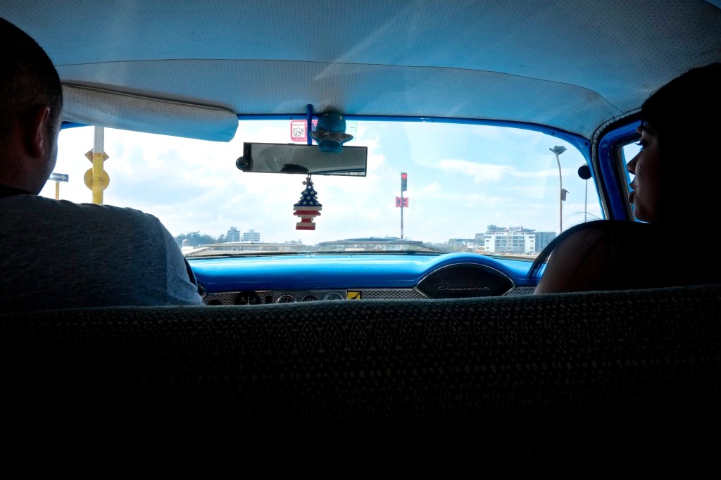An American flag air freshener hangs from the rearview mirror of a cab. 