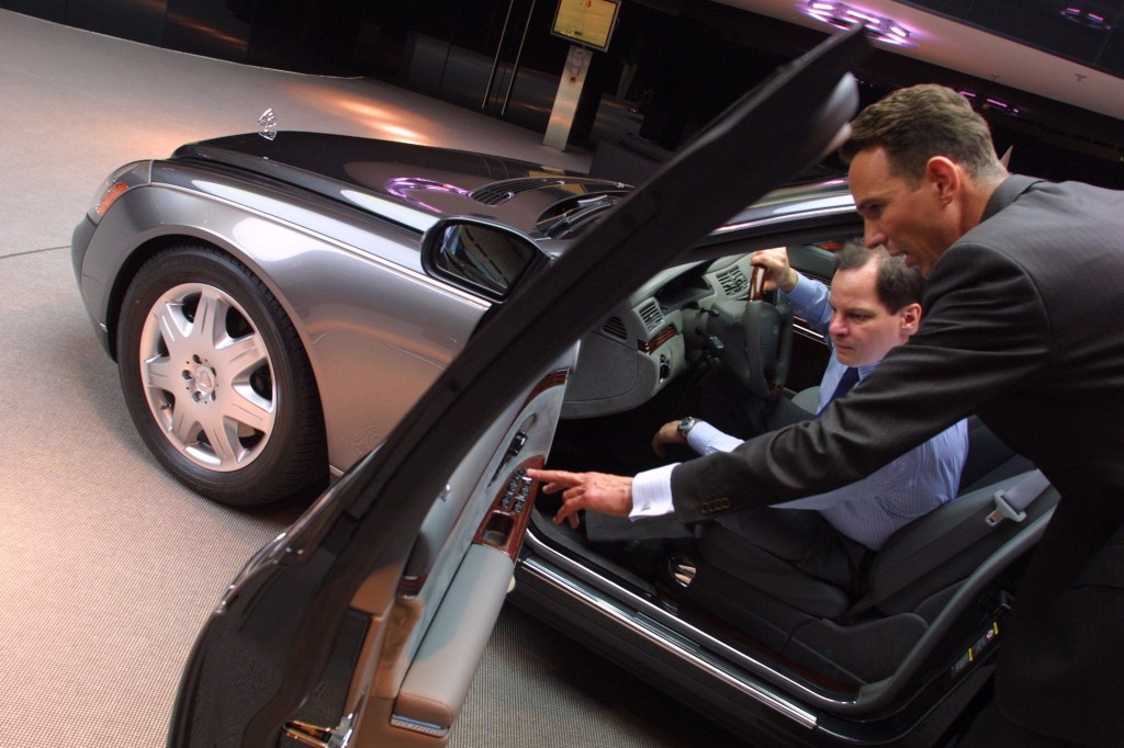 A salesman shows a potential customer detail on a Maybach 57 limousine.