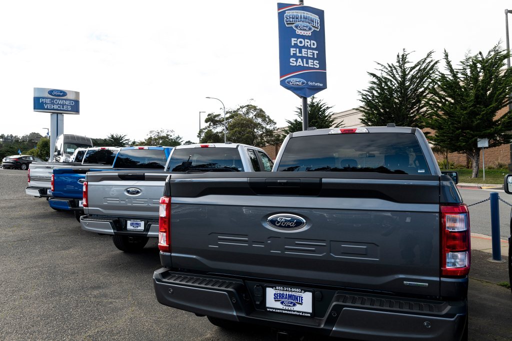 Ford dealership lot with new Ford F-150s, Ford Super Duty, and others lined up to be sold 