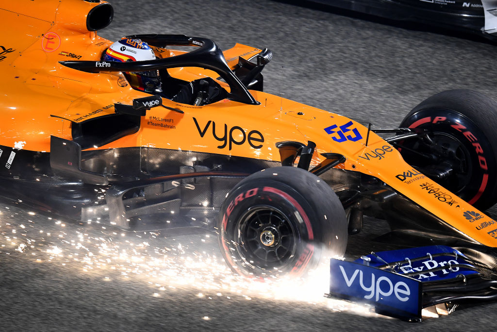An orange Formula1 racecar sparking as it races down the track