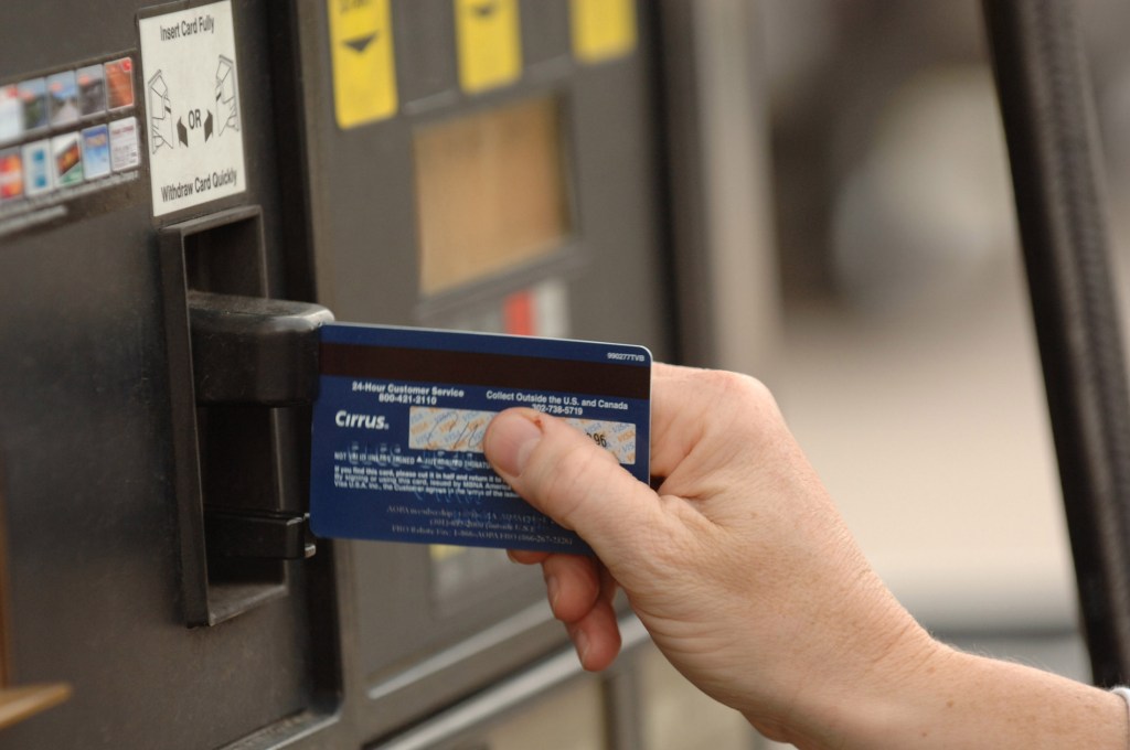 A customer swipes her credit card at a gas pump in a Conoco gas station. 
