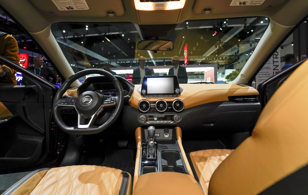 The tan interior of a nissan sentra as shown from behind the drivers seat