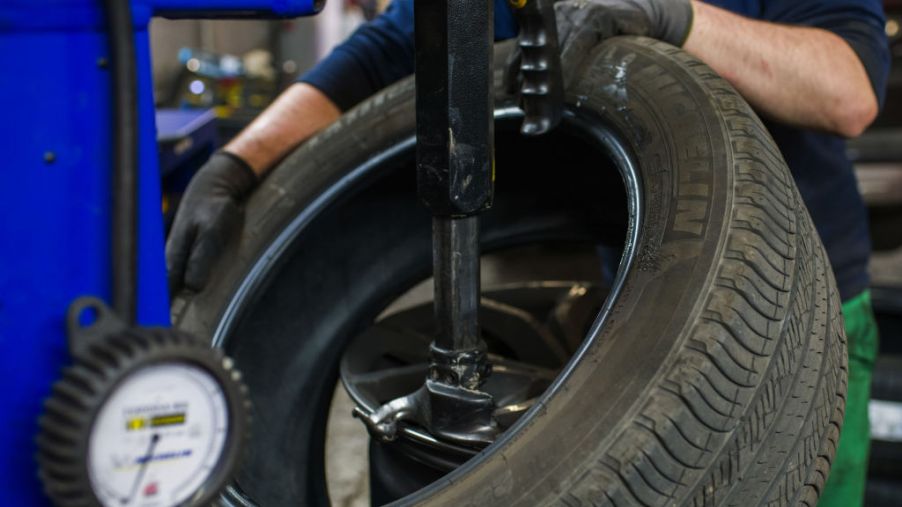 A mechanic puts a tire onto a wheel