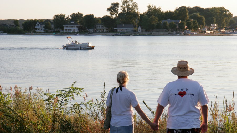 A couple holds hands while looking at a pontoon boat on Pine Lake in La Porte, Indiana