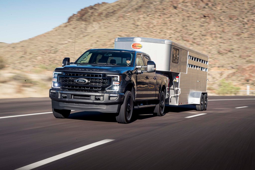 A blue 2020 Ford F-150 hauling a silver trailer in a hilly area 