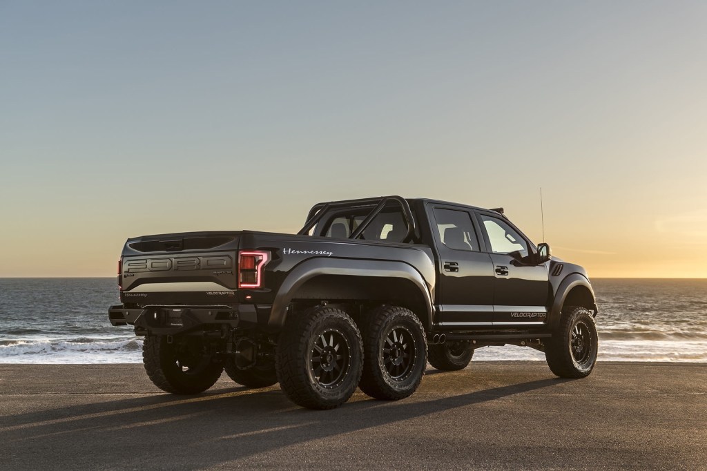 a black Hennessey Velociraptor 6x6 parked on the beach as one of the biggest pickup trucks ever