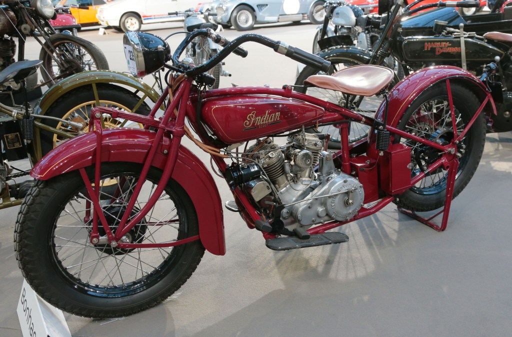 A red 1928 Indian 101 Scout displayed by some other antique motorcycles and cars