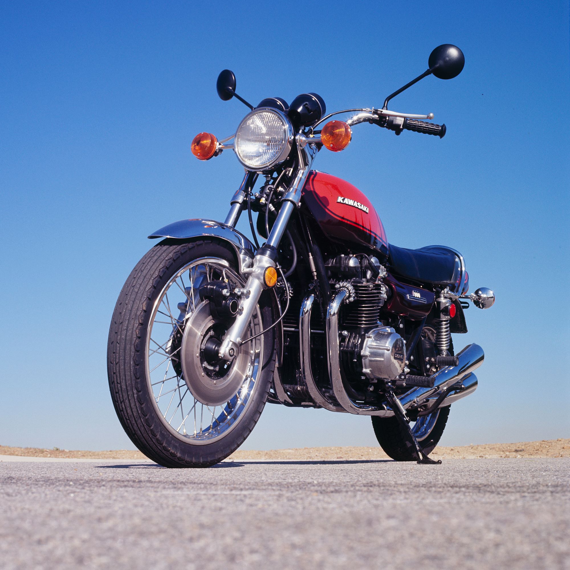A low-angle front 3/4 view of an orange-and-brown 1973 Kawasaki Z1 900 on a desert road