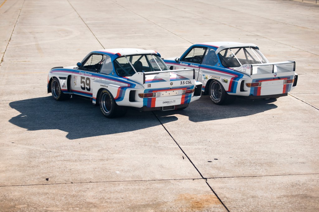 The rear 3/4 view of the No. 59 1976 BMW 3.0 CSL Batmobile next to the No. 26 1975 BMW 3.0 CSL Batmobile