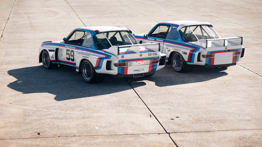 The rear 3/4 view of the No. 59 1976 BMW 3.0 CSL Batmobile next to the No. 26 1975 BMW 3.0 CSL Batmobile