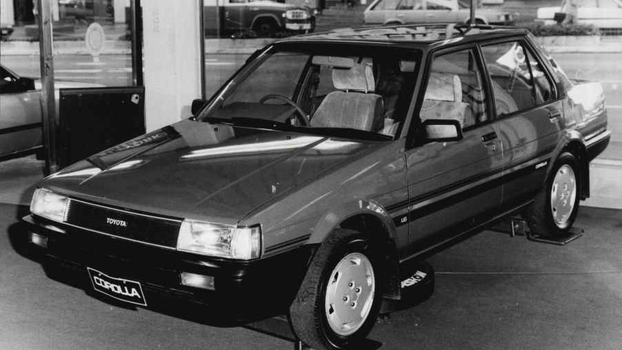 A black-and-white-photo of a Toyota Corolla compact sedan in a showroom on June 11, 1985