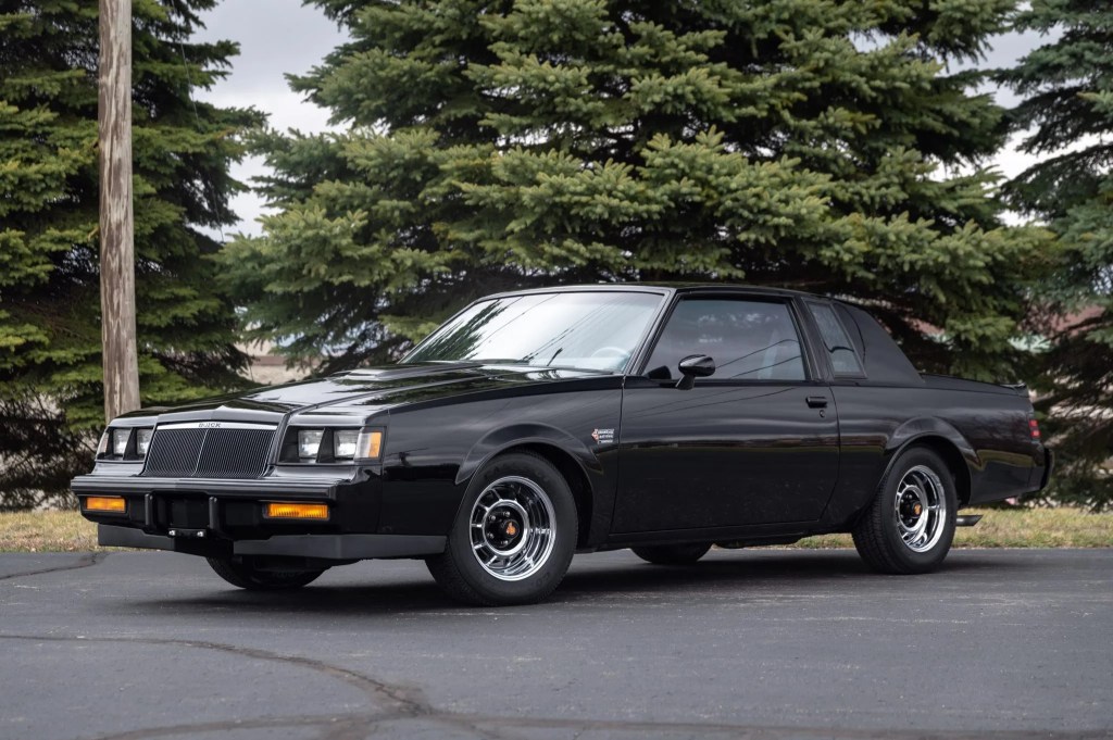 A black 1986 Buick Grand National in a tree-lined parking lot