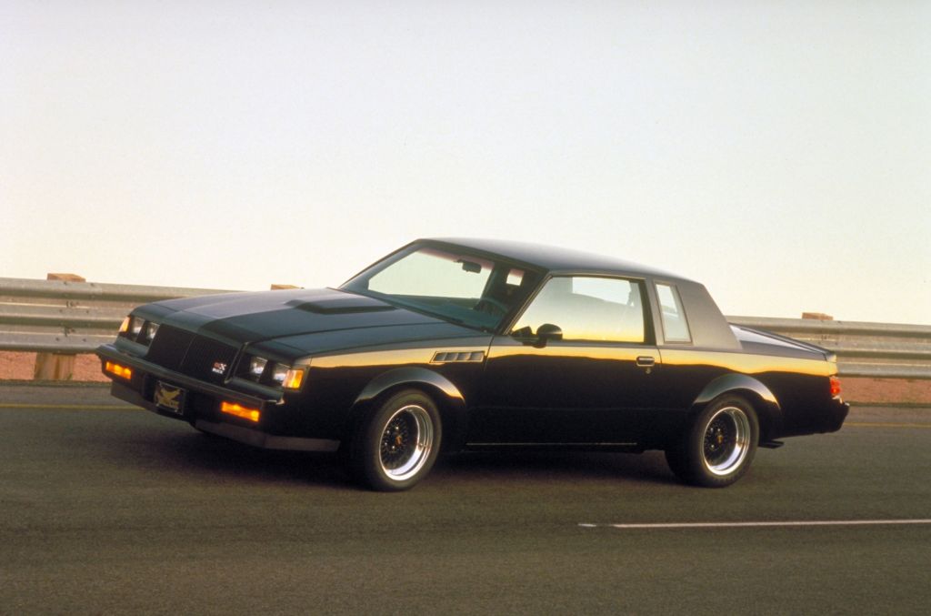 A black 1987 Buick GNX drives at high speeds down a road