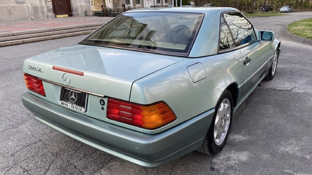 The rear 3/4 view of a two-tone-green 1991 Mercedes-Benz 300 SL with a hardtop and a 500 SL badge in a park parking lot