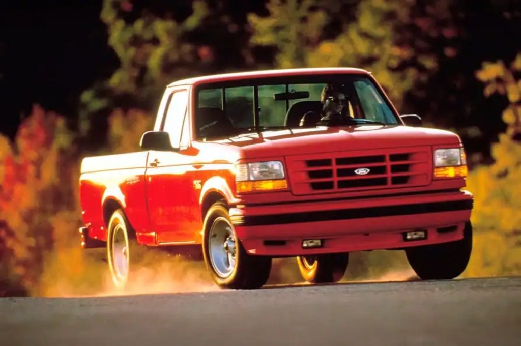 A red 1993 Ford SVT F-150 Lightning kicks up some dust driving down the road