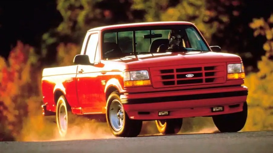 A red 1993 Ford SVT F-150 Lightning kicks up some dust driving down the road