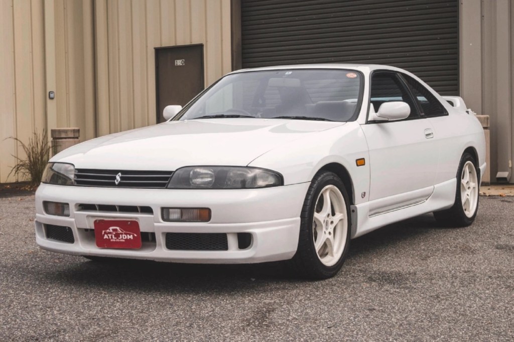 A white 1994 R33 Nissan Skyline GTS-25t parked by a building