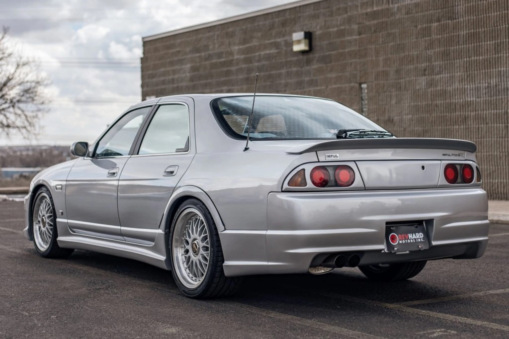 The rear 3/4 view of a silver 1995 Nissan Skyline Impul R33-R in a parking lot
