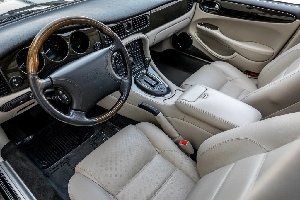 The white-leather front seats and dark-wood-trimmed dashboard of a 1998 Jaguar XJR