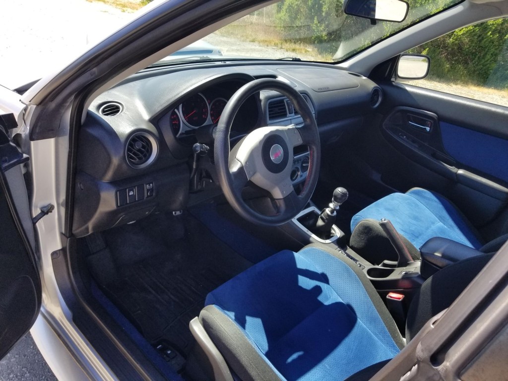 The blue-and-black front sport seats and black dashboard of a 2004 Subaru Impreza WRX STi