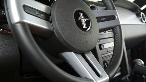 A black and silver three-spoke steering wheel inside a 2005 Ford Mustang GT