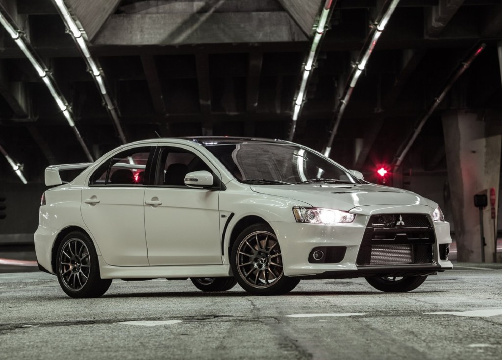 A white 2015 Mitsubishi Lancer Evolution Final Edition underneath a lit concrete city bridge