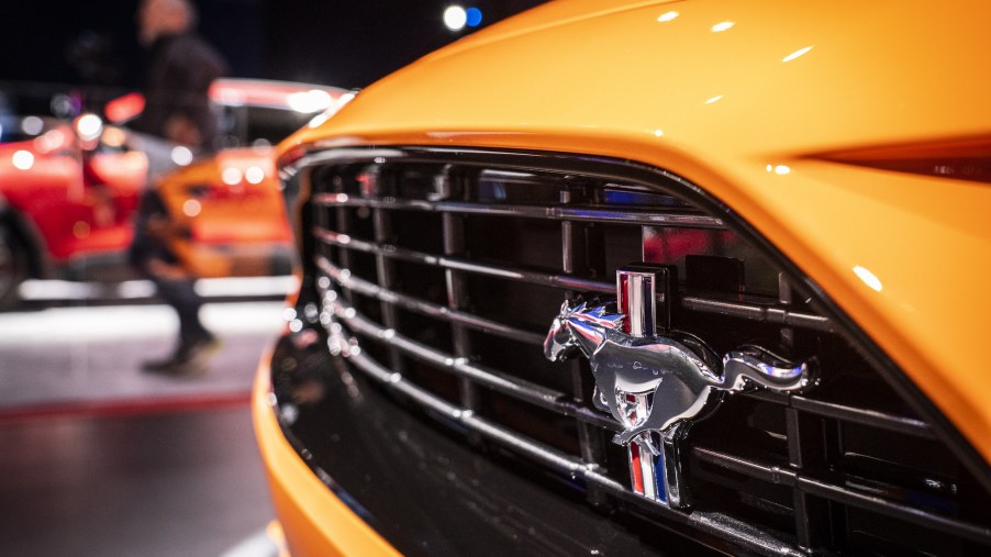 A logo is displayed on the grille of an orange Ford Mustang at the 2019 New York International Auto Show