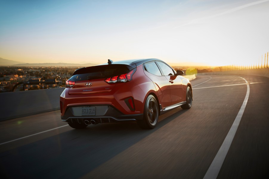 An orange 2019 Hyundai Veloster Turbo hatchback traveling on a road above a city