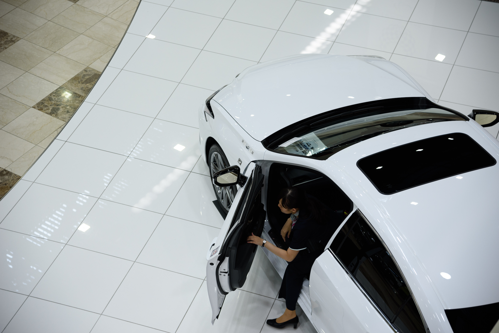 An employee comes out from a white 2019 Lexus ES 300h luxury car at the company's showroom in Toyota City, Aichi Prefecture, Japan, on Wednesday, June 12, 2019