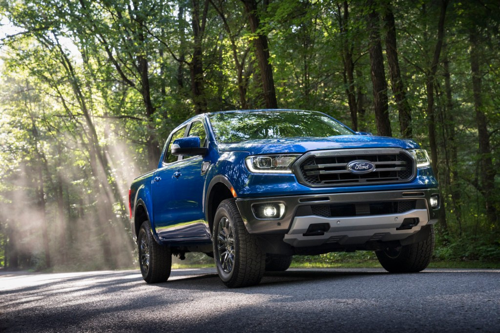 A blue 2020 Ford Ranger parked on a sun-dappled road in a forest