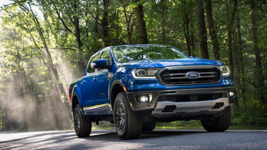 A blue 2020 Ford Ranger parked on a sun-dappled road in a forest