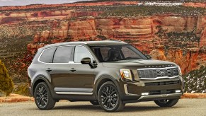 A dark-green 2020 Kia Telluride midsize crossover SUV parked in front of a red butte and mountains