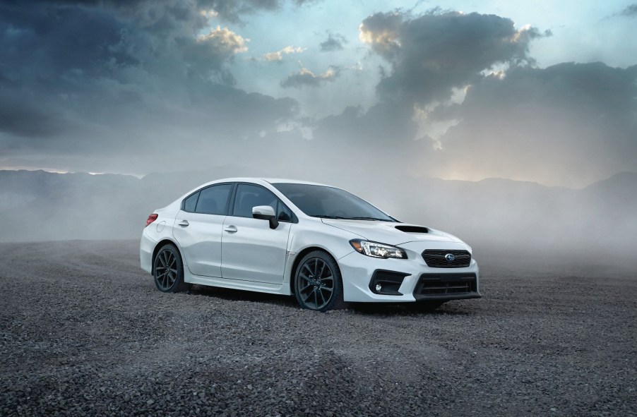 A whtie 2020 Subaru WRX four-door sports car surrounded by smoke with a cloudy sky in the background