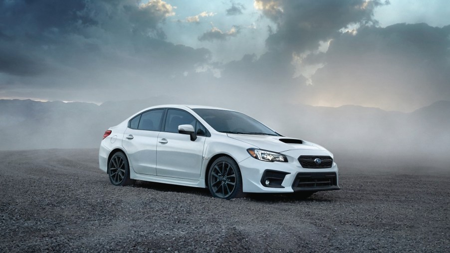 A whtie 2020 Subaru WRX four-door sports car surrounded by smoke with a cloudy sky in the background