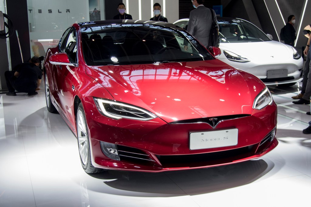 A shiny red 2020 Tesla Model S sits in the spotlight and is highlighted in Consumer Reports cars to avoid buying list.