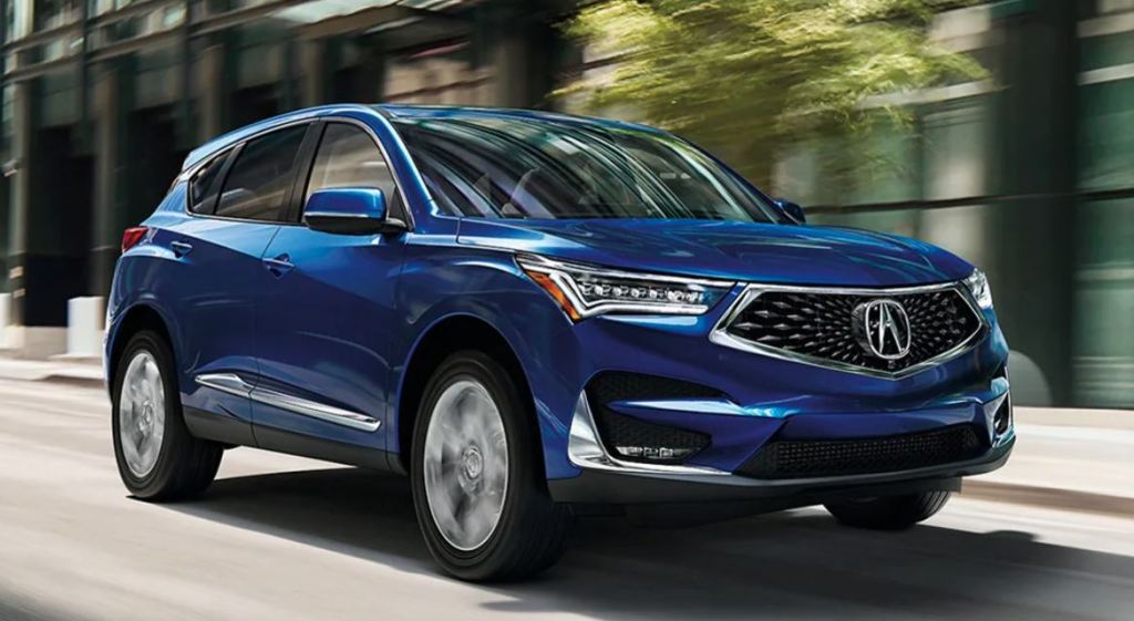 An Acura RDX, one of the safest midsize luxury SUVs, driving down a city street.