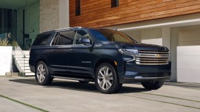 a blue 2021 Chevrolet suburban parked in front a modern garage with wood detail on the structure above