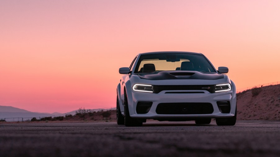A white and black 2021 Dodge Charger parked in front of mountains at sunset