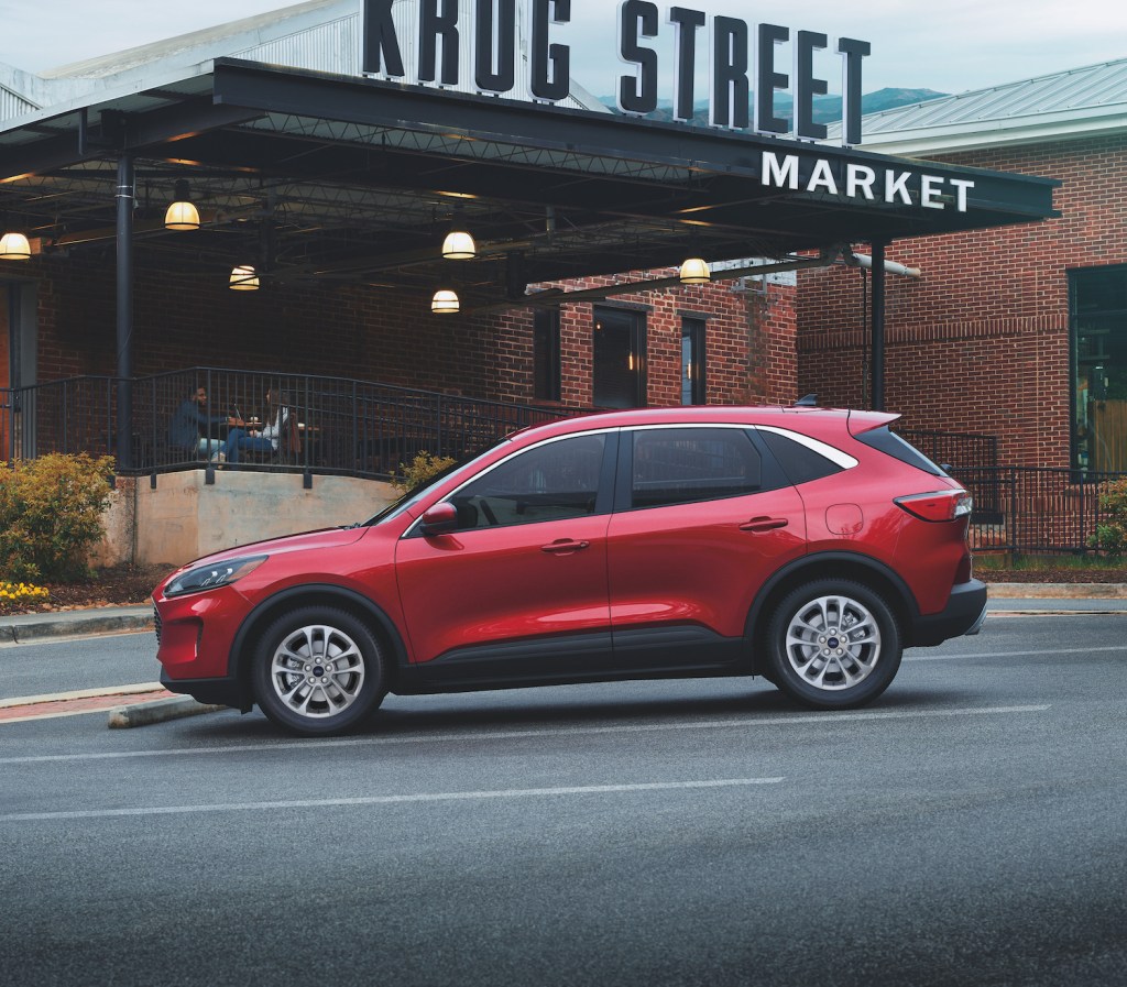 A red 2021 Ford Escape Hybrid parked in front of a market