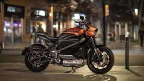 An orange-and-black 2021 Harley-Davidson LiveWire parked on a city street at night